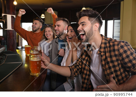 Group of friends watching football in sport bar Group of friends watching football in sport bar 90995744