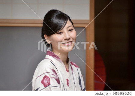 町屋の縁側で微笑む浴衣を着た若い女性 90998626