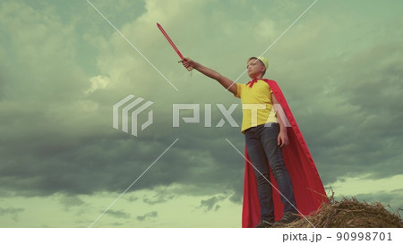 teenage boy plays knight against background sky. concept children play. childhood dream superhero. defend himself with sword crown his head. superman winner. fantasy childhood dream. red cape wind. teenage boy plays knight against background sky. concept children play. childhood dream superhero. defend himself with sword crown his head. superman winner. fantasy childhood dream. red cape wind. 90998701
