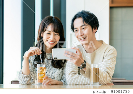 カフェで動画を見る若いカップル カフェで動画を見る若いカップル 91001759