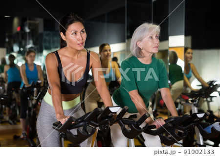 Two woman at group training on fitness bikes 91002133