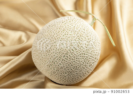 シャンパンゴールドのシルク生地の背景にアールスメロン 91002653