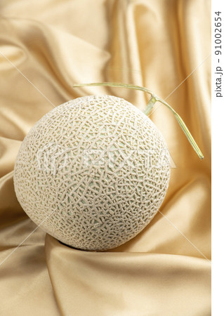 シャンパンゴールドのシルク生地の背景にアールスメロン 91002654