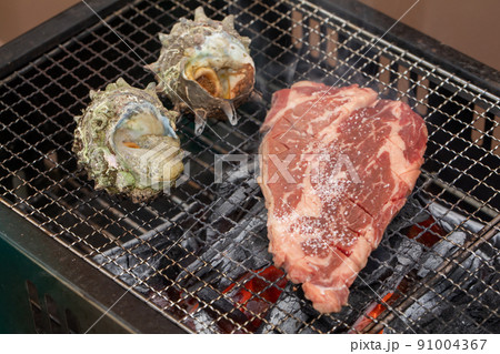 炭火で焼かれるサザエと牛肉 Turban shell and beef 炭火で焼かれるサザエと牛肉 Turban shell and beef 91004367