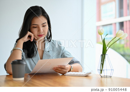 Beautiful asian female accountant checking, reading, analysing the report paper Beautiful asian female accountant checking, reading, analysing the report paper 91005448