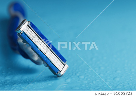 Razor blades on a blue background with drops of icy water 91005722