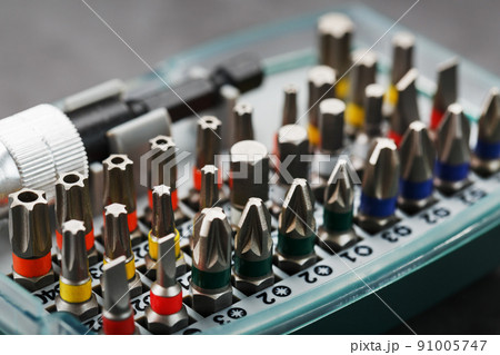 A set of different bits for screwdrivers and repairs in a box on a gray background A set of different bits for screwdrivers and repairs in a box on a gray background 91005747