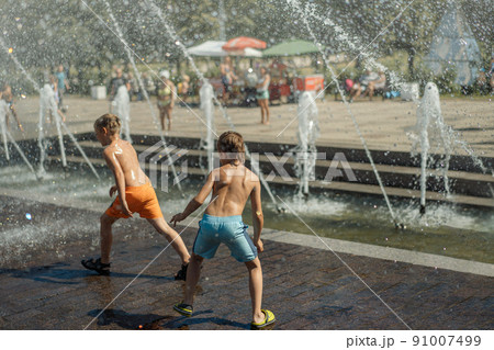 Three caucasian boys going to run throgh splashing fountain on hot summer day in city of Saint-petersburg, Russia Three caucasian boys going to run throgh splashing fountain on hot summer day in city of Saint-petersburg, Russia 91007499
