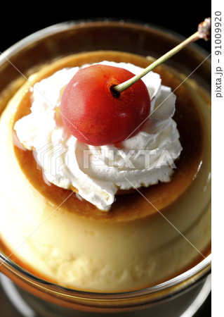 サンデーカップに盛り付けてある生クリーム、チェリーの乗った昔ながらのレトロプリンを黒背景で俯瞰撮影 91009920
