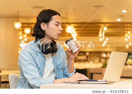 黒いヘッドフォンを付けた男性（ノートパソコン、コーヒー 91010651