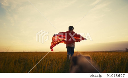 girl superhero. child in a red raincoat runs with a dog outdoors in the park. happy family kid lifestyle dream concept. little girl superhero runs with a dog across the field in nature 91013697