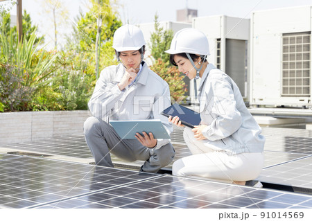ソーラーパネルをチェックするビジネスマンと女性作業員 91014569