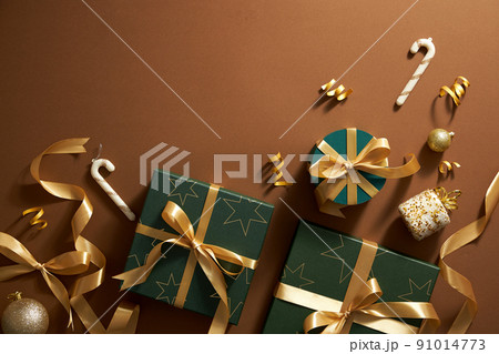 Top view of christmas ornament in brown background , gift box with yellow ribbon and twinkle yellow pearl with middle blank space for holiday Top view of christmas ornament in brown background , gift box with yellow ribbon and twinkle yellow pearl with middle blank space for holiday 91014773