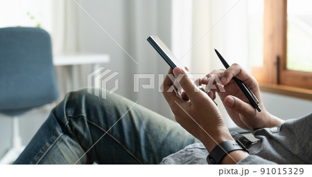 Cropped shot of businessman using mobile phone while sitting in modern office. Cropped shot of businessman using mobile phone while sitting in modern office. 91015329