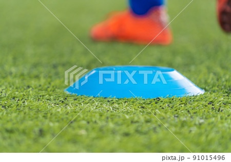 Sport Cone Marker for soccer training on a artifact field closed up shot Sport Cone Marker for soccer training on a artifact field closed up shot 91015496