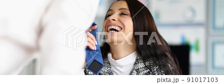 Businesswoman flirting with corporate male worker touching his tie and laughing 91017103