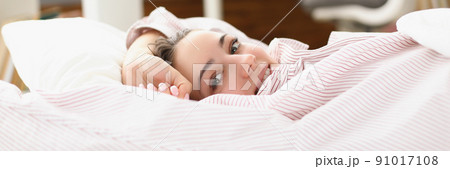 Happy young woman waking up in cozy home bed in good mood 91017108