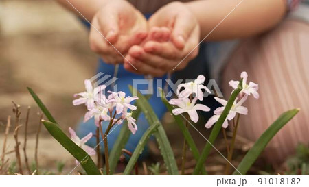 a little girl watering flowers from the palms of her hands. 91018182