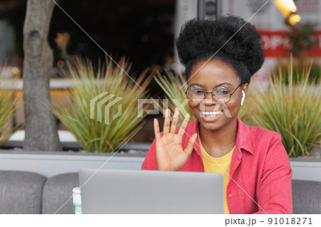 African American woman works on a laptop in a coworking or office, watches a training webinar, participates in a video conference 91018271