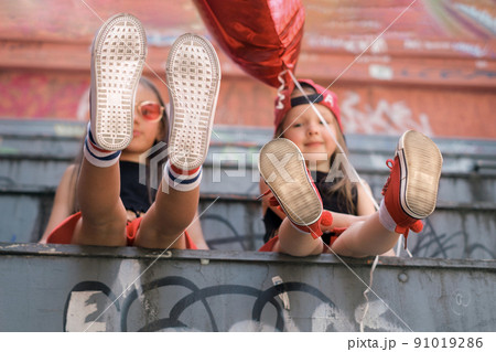 The soles of children's sneakers are close-up on the feet of smiling hippie girls. The soles of children's sneakers are close-up on the feet of smiling hippie girls. 91019286