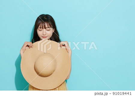 リゾートファッションをした若い女性の青背景のポートレート 91019441