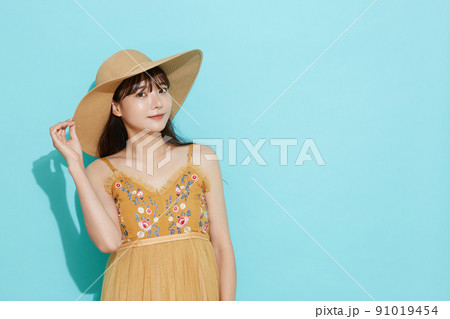 リゾートファッションをした若い女性の青背景のポートレート 91019454