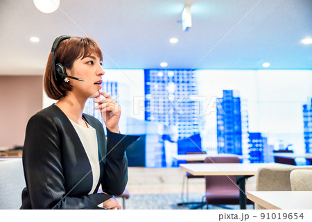 フリーアドレスオフィスで仕事をするヘッドセットをしたビジネスパーソン フリーアドレスオフィスで仕事をするヘッドセットをしたビジネスパーソン 91019654