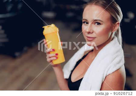 Young sporty woman having a drink in a gym after workout Young sporty woman having a drink in a gym after workout 91020712