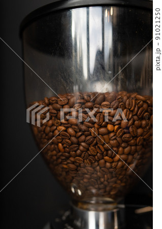 Coffee beans roasted and poured into a coffee grinder. The process of making coffee by a barista. Close-up. Coffee beans roasted and poured into a coffee grinder. The process of making coffee by a barista. Close-up. 91021250