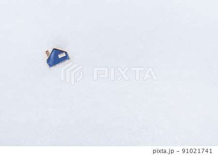 A metal small blue house that lies on the snow. Place for an inscription. Real estate and mortgage concept. 91021741