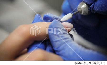 Manicurist doing hardware manicure to female client using special apparatus 91022913