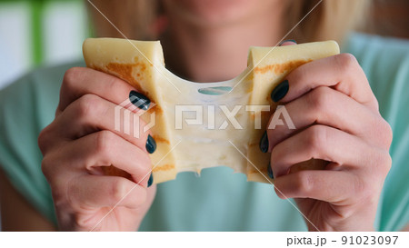 Female hands holding pancake with cheese filling 91023097