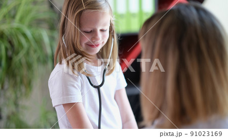 Smiling little kid testing medical stethoscope at doctor appointment Smiling little kid testing medical stethoscope at doctor appointment 91023169