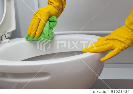 Hands in yellow gloves cleaning a WC 91023484