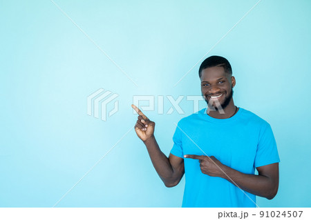 Advertising man. Discount promotion. Offer recommendation. Cheerful guy presenting product pointing finger on blue copy space background. 91024507