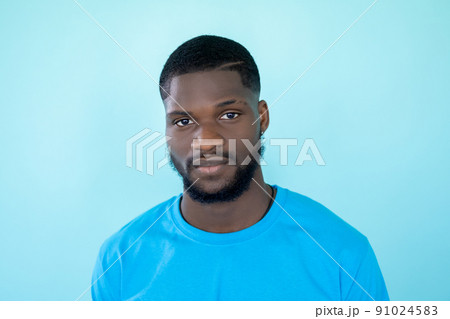 Man face. Studio portrait. Neutral expression. Headshot of handsome young beardy calm emotion guy isolated on light blue free space background. 91024583