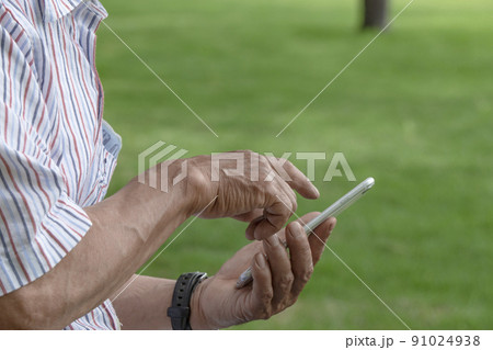 公園でスマホを使っている年配の男性 公園でスマホを使っている年配の男性 91024938