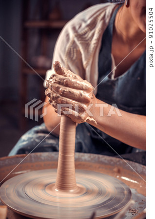 Potter master woman creates a new pottery from clay on a potter's wheel. Handicraft. Close-up. 91025504
