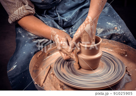 Craftsman siting on bench with pottery wheel and making clay pot. National craft. Close-up. 91025905