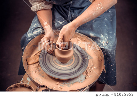The potter works in the workshop. Hands and a potter's wheel close-up 91025955
