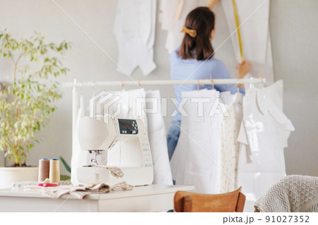 woman sews clothes on a sewing machine in a workshop. work in the production of clothing and textiles. patterns and fabrics for sewing 91027352