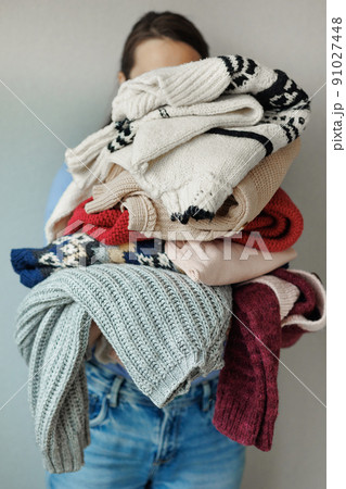 woman holds colored sweaters and clothes in her hands. washing and care of clothes, powder and conditioner for washing. a happy woman stylist woman holds colored sweaters and clothes in her hands. washing and care of clothes, powder and conditioner for washing. a happy woman stylist 91027448