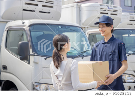 担当地域の配達員に荷物を渡す事務員 91028215