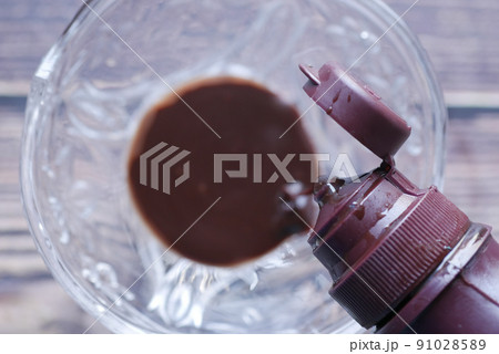 dark chocolate syrup pouring from a bottle  91028589