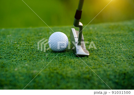 Golf clubs and golf balls on a green lawn in a beautiful golf course with morning sunshine. 91031500