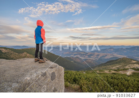 Young child boy hiker standing in mountains enjoying view of amazing mountain landscape. 91033627