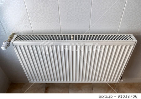 White metal heating radiator mounted on a wall in room interior. 91033706