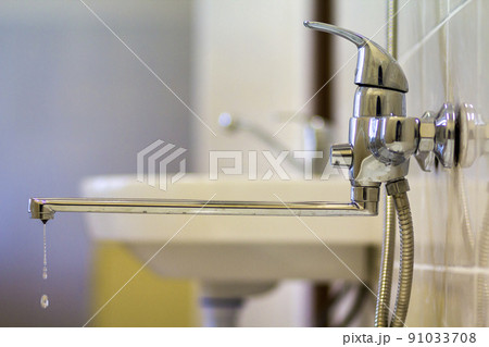 Water tap, chrome stainless metal faucet with running water stream connected to shower stall tiled wall, mixer cold hot water on blurred bathroom background. Modern home interior. 91033708