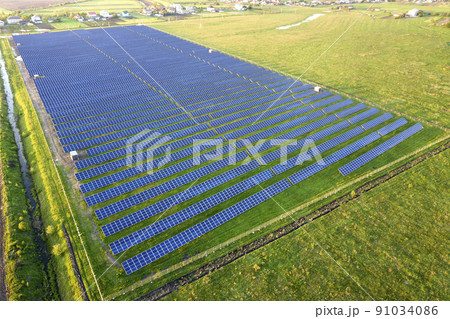 Large field of solar photo voltaic panels system producing renewable clean energy on green grass background. 91034086