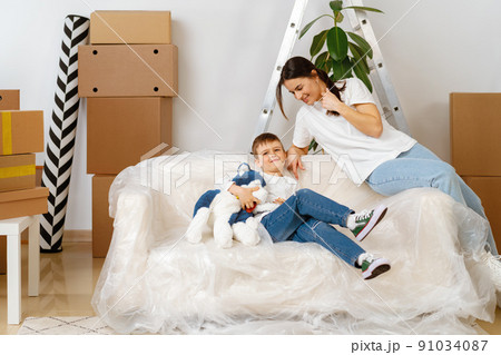 Beautiful smiling woman and little boy with cardboard boxes moving to new home 91034087